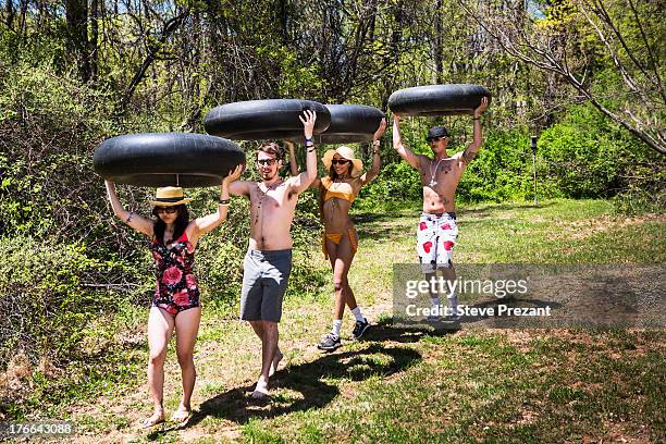 four people carrying inner tubes above heads - inner tube stock-fotos und bilder