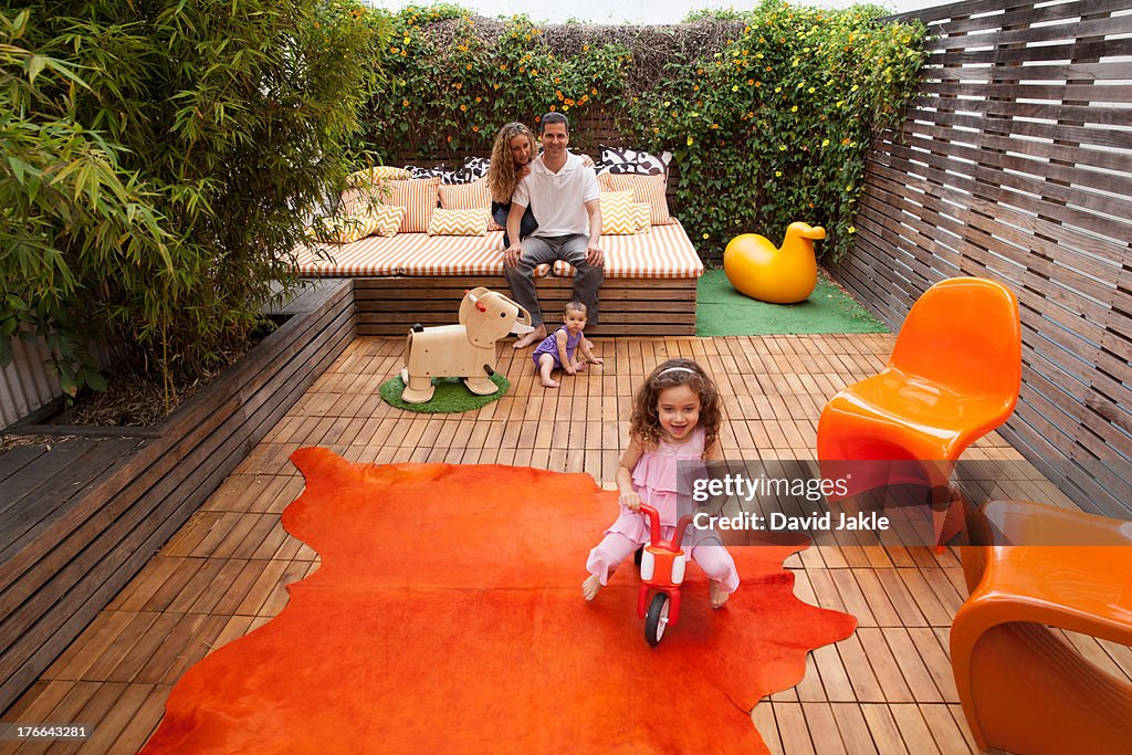 Parents relaxing outdoor with children playing on patio