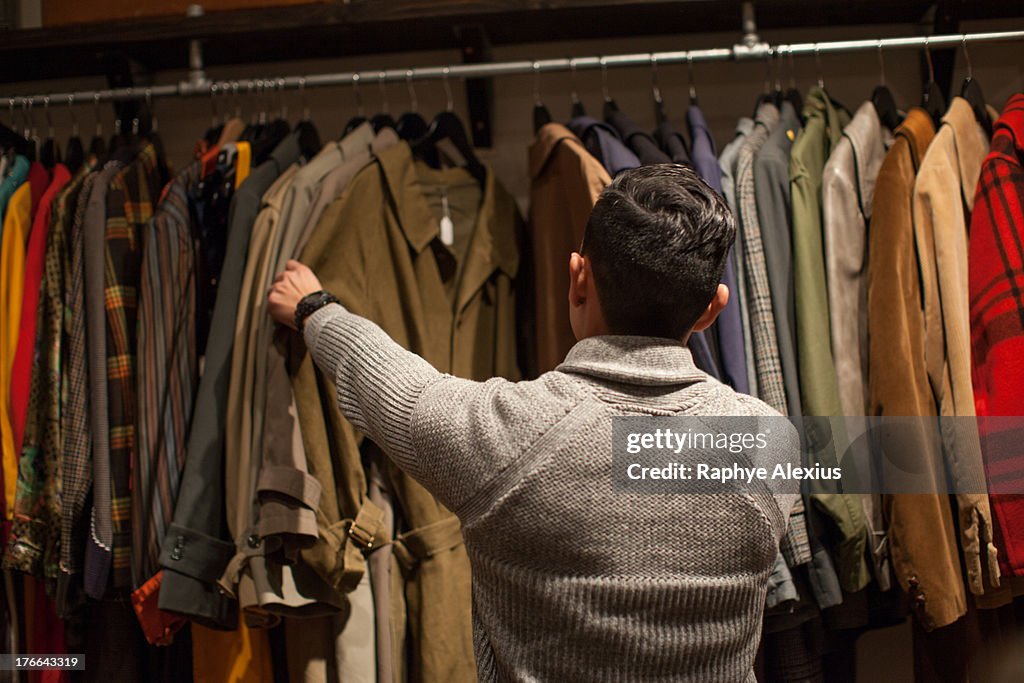 Young man looking through clothes rail in vintage shop