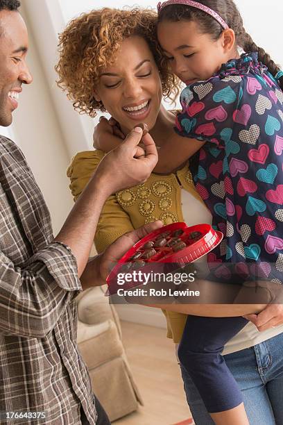 parents and daughter with heart shaped chocolate box - sharing chocolate stock-fotos und bilder