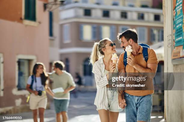 happy couple of tourists talking while eating ice-cream on the street. - rovinj stock pictures, royalty-free photos & images