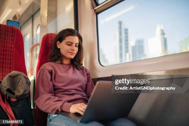 estudiante universitaria usando una computadora portátil en el tren de camino a clase. - tren de pasajeros fotografías e imágenes de stock