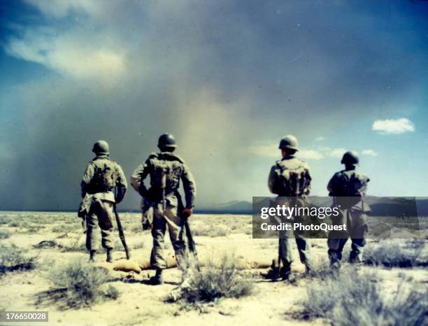 Four men from the 82nd Airborne Division looking at the base of the mushroom cloud of 'Big Shot', an atomic bomb test, from the observers' foxhole...