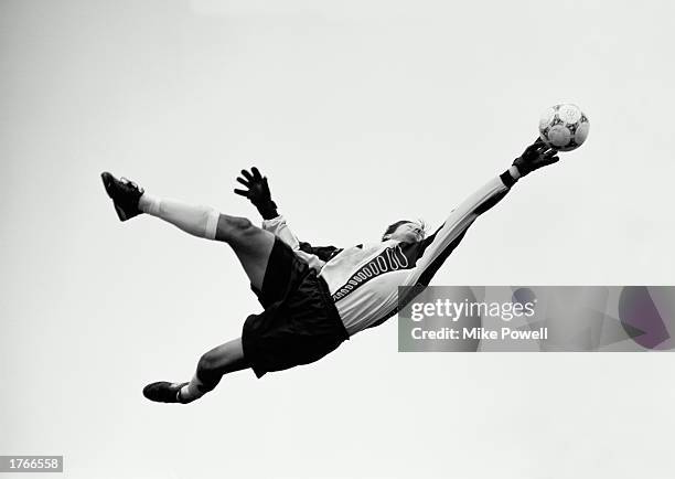 Football, goalkeeper in mid-air jump reaching for ball