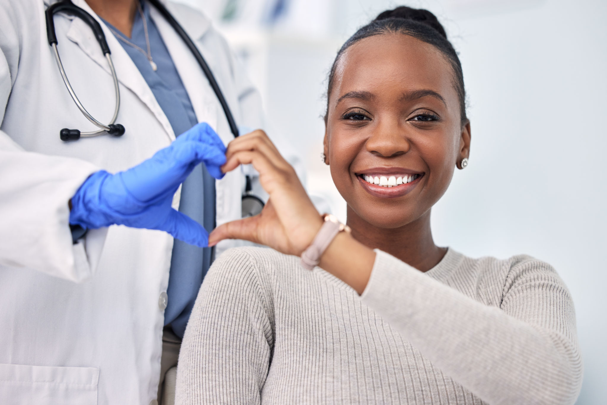 Black woman, patient and doctor with smile, consultation and heart emoji for cardio health, checkup and appointment. Happiness, support and wellness for medicine, healthcare and physical examination Black woman, patient and doctor with smile, consultation and heart emoji for cardio health, checkup and appointment. Happiness, support and wellness for medicine, healthcare and physical examination