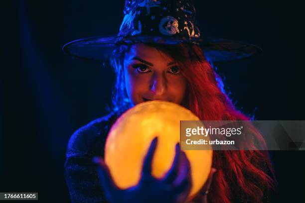 mulher nova vestida como uma bruxa segurando uma bola de cristal - wizard - fotografias e filmes do acervo