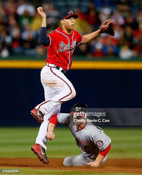 Andrelton Simmons of the Atlanta Braves attempts to turn a double play over Chad Tracy of the Washington Nationals in the ninth inning at Turner...