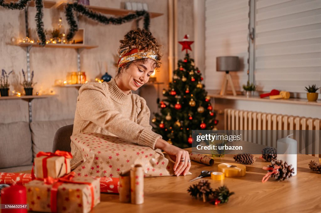 Young Woman Wrapping Christmas Gifts At Home