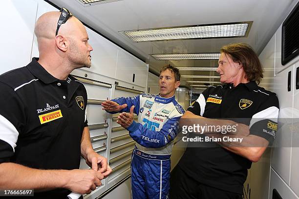 Scott Pruett, , talks to Bruce Jenner, R, and Burt Jenner, L, in the paddock during practice for the SPF Grand Prix at Kansas Speedway in Kansas...