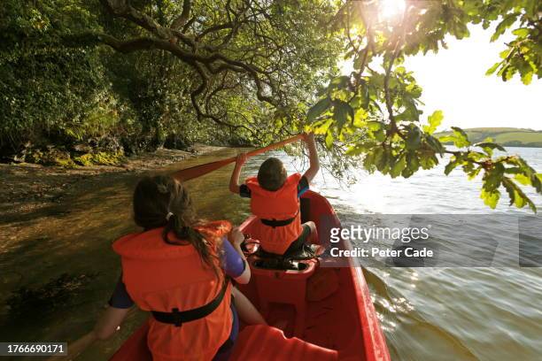 two children in kayak on river - family red canoe stock pictures, royalty-free photos & images