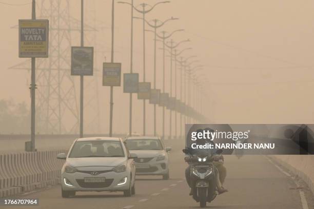 Commuters make their way along a road amid heavy smoggy conditions in Amritsar on November 6, 2023.