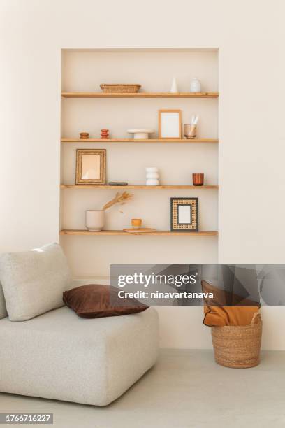 comfortable chair in a living room next to shelves with assorted ornaments, vases and mirrors - continental_shelf stock pictures, royalty-free photos & images