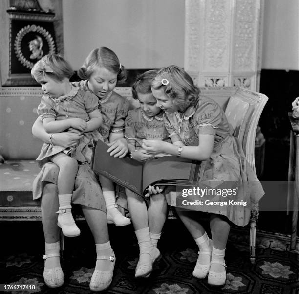 The four daughters of Queen Juliana of the Netherlands seated on a sofa with a photo album at Soestdijk Palace in Baarn, November 1950. They are :...