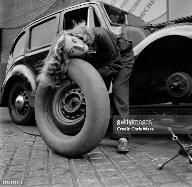 Mechanic Eileen Hayman posing with a car tyre's inner tube at her father's garage in Ipswich, Suffolk, October 1951. She believes she is the only...