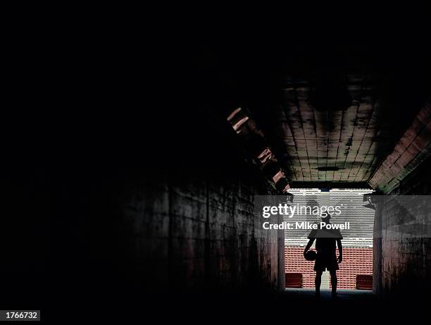 Silhouette of soccer player standing at end of stadium tunnel