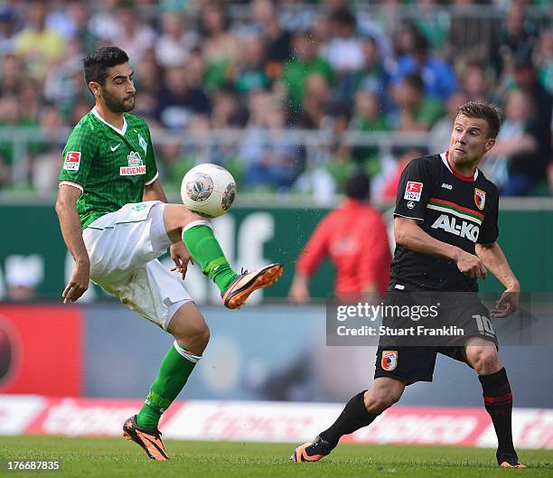 Mehmet Ekici of Bremen is challenged by Daniel Baier of Augsburg during the Bundesliga match between Werder Bremen and FC Augsburg at Weserstadion on...