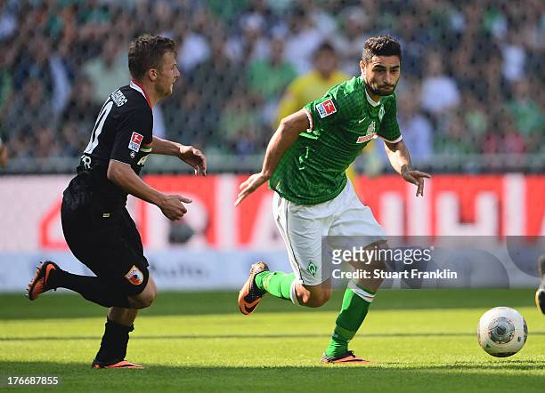 Mehmet Ekici of Bremen is challenged by Daniel Baier of Augsburg during the Bundesliga match between Werder Bremen and FC Augsburg at Weserstadion on...