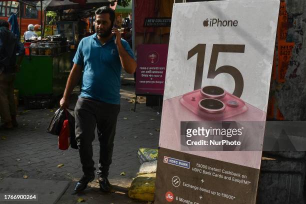 Man talking on phone walks past a advertisement of Apple Iphone 15 , as seen in Kolkata , India , on 6 November 2023 . Apple recorded over 89.5...