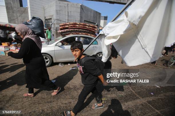 Palestinian boy carries a make-shift white flag as he arrives with his mother near the Al-Shifa hospital in Gaza City on November 6 amid ongoing...
