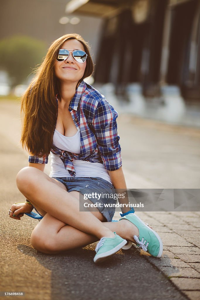 Smiling hipster sitting on skateboard