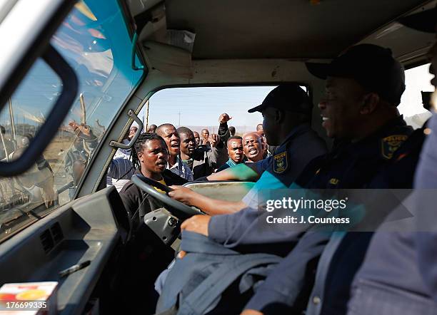 Miners and supporters of the Marikana mining community ask police forces to leave the area as they march near the Lonmin Platinum Mine to commiserate...