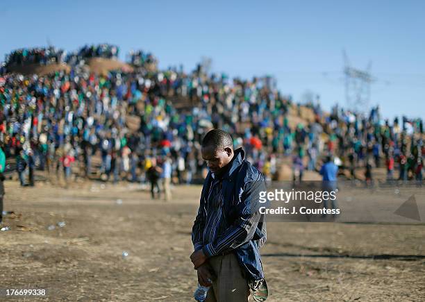 Man joins miners and supporters of the Marikana mining community in prayer during a memorial to commiserate the one year anniversary of the massacre...