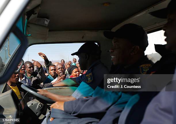 Miners and supporters of the Marikana mining community ask police forces to leave the area as they march near the Lonmin Platinum Mine to commiserate...