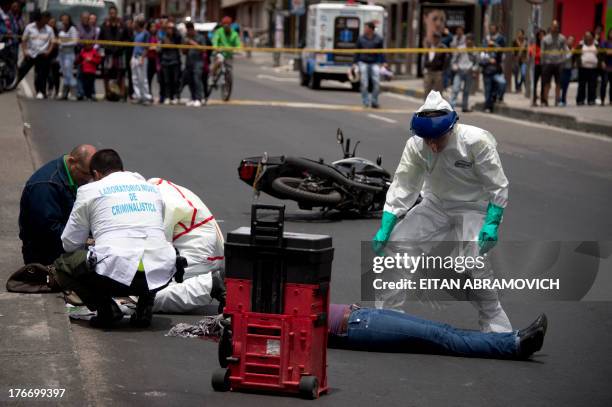 Forensic personnel work on the scene of a motorcycle accident in which a woman was killed in Bogota on August 17, 2013. According to Bogota's...