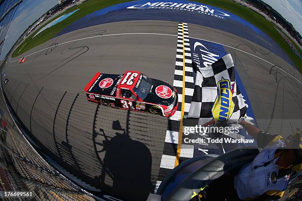 James Buescher, driver of the Rheem Chevrolet, crosses the finish line to win the NASCAR Camping World Truck Series 14th Annual Michigan National...