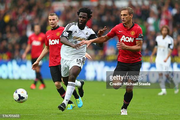 Wilfried Bony of Swansea City is tracked by Nemanja Vidic of Manchester United during the Barclays Premier League match between Swansea City and...