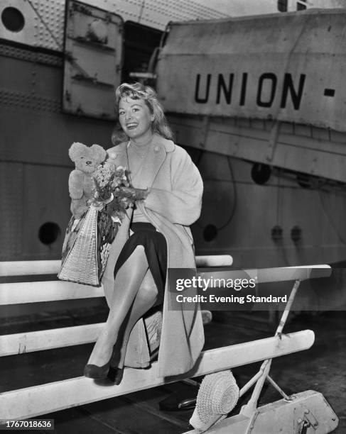 British actress Shirley Burniston holding a teddy bear on arrival at an English port, January 1st 1958.