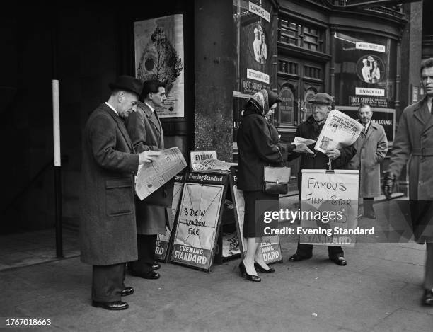 Man selling copies of the Evening Standard newspaper in London, February 5th 1958. The board he is holding reads 'Famous Film Star Convicted'.