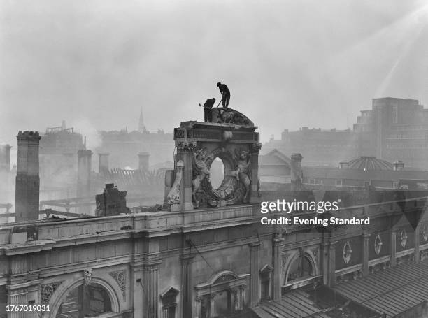 Two workers atop a wall at Smithfield Meat Market which was severely damaged in a recent fire, London, February 4th 1958. The blaze started on...