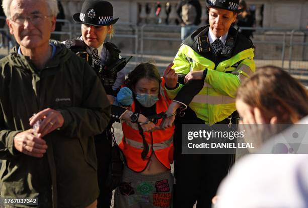 Just Stop Oil climate activist is arrested by Metropolitan Police officers after taking part in a slow march to disrupt traffic, on Whitehall in...