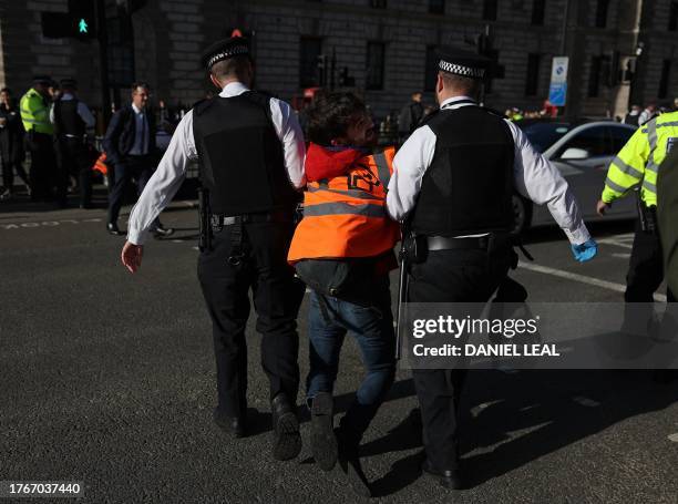 Just Stop Oil climate activist is arrested by Metropolitan Police officers after taking part in a slow march to disrupt traffic, on Whitehall in...