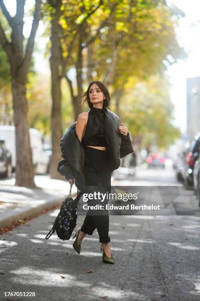 Heart Evangelista wears a black oversized leather puff / bomber jacket from Saint Laurent YSL, a black crop halter top from Sau Lee, black pants from...