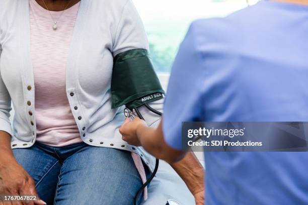 unrecognizable healthcare professional uses blood pressure cuff to check vitals - blood pressure gauge stock pictures, royalty-free photos & images