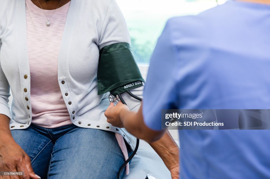 Unrecognizable healthcare professional uses blood pressure cuff to check vitals