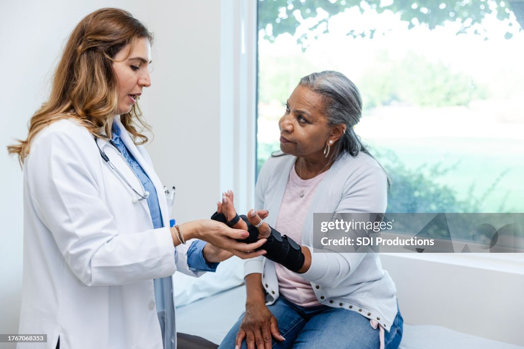 Cirurgiã ortopédica conversa com paciente madura sobre sua lesão