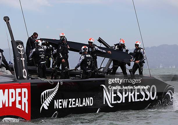 Crew members from Emirates Team New Zealand skippered by Dean Barker removed a section of tarp from their AC-72 catamaran that was damaged during...