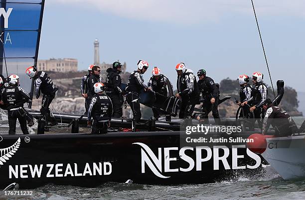 Crew members from Emirates Team New Zealand skippered by Dean Barker removed a section of tarp from their AC-72 catamaran that was damaged during...