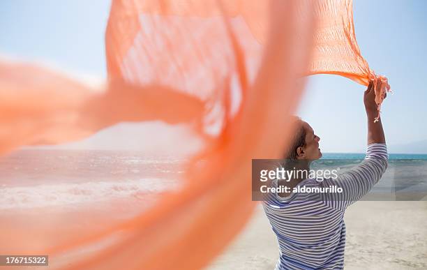 beautiful senior woman on the beach - woman flying scarf stock pictures, royalty-free photos & images