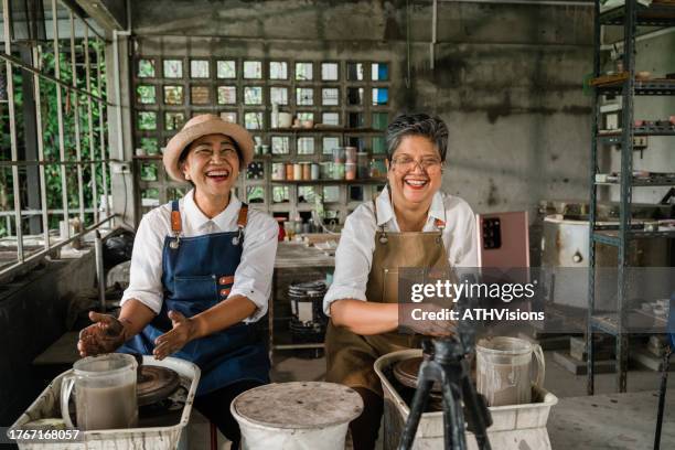 two senior women friends smile and laughing pottery classes while live streaming on smart phone. - east asian works of art specialist stock pictures, royalty-free photos & images