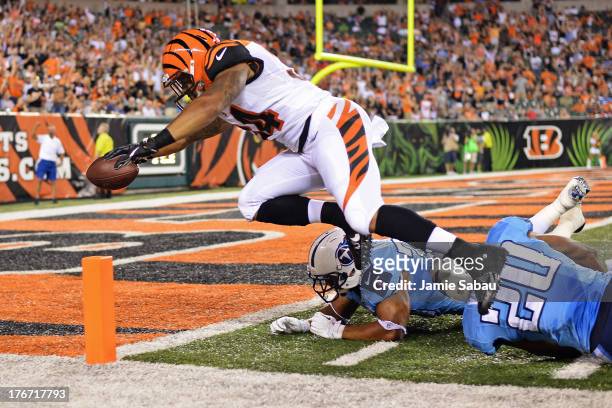 Dan Herron of the Cincinnati Bengals leaps in to the end zone to complete a 40-yard touchdown run past Al Afalava of the Tennessee Titans and...