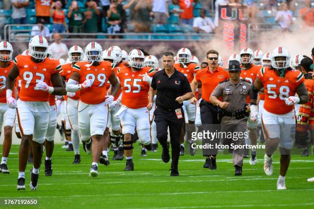Miami head coach Mario Cristobal runs on to the field with defensive line Anthony Campbell , defensive line Ahmad Moten , center Matt Lee and the...
