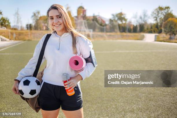 portrait of young woman prepared for football training holding exercise mat - calções de corrida imagens e fotografias de stock