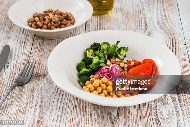 vegan salad with roasted red bell peppers, chickpeas, hazelnuts, broccoli, healthy plant based meal - salad bowl stock pictures, royalty-free photos & images