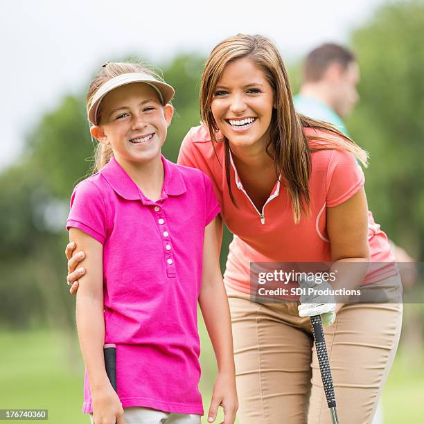 mom & daughter playing golf together on course - golf clubhouse stockfoto's en -beelden