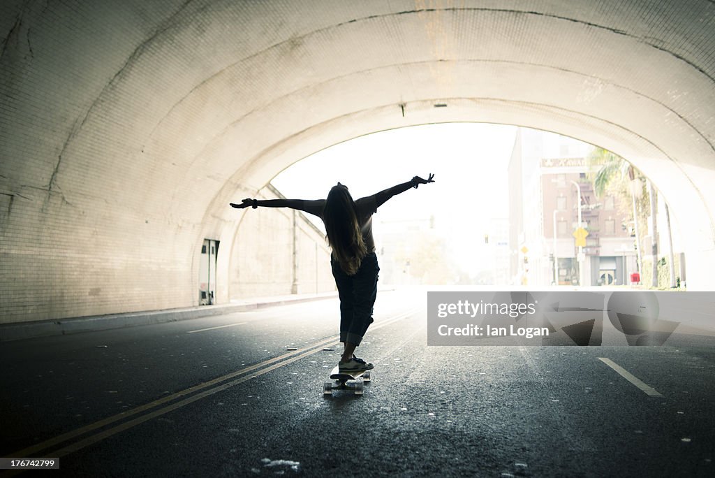 Woman skateboarding in tunnel