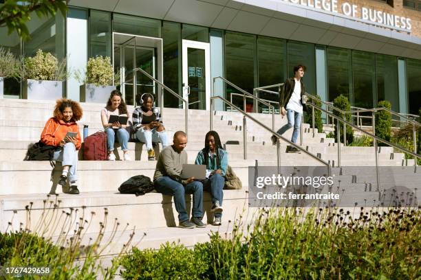 gruppe von studenten sitzt vor dem universitätsgebäude - campus stock-fotos und bilder